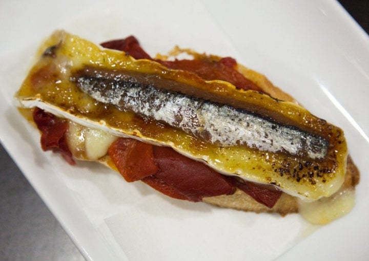 El canapé de anchoa sobre una cama de tomate macerado en aceite.