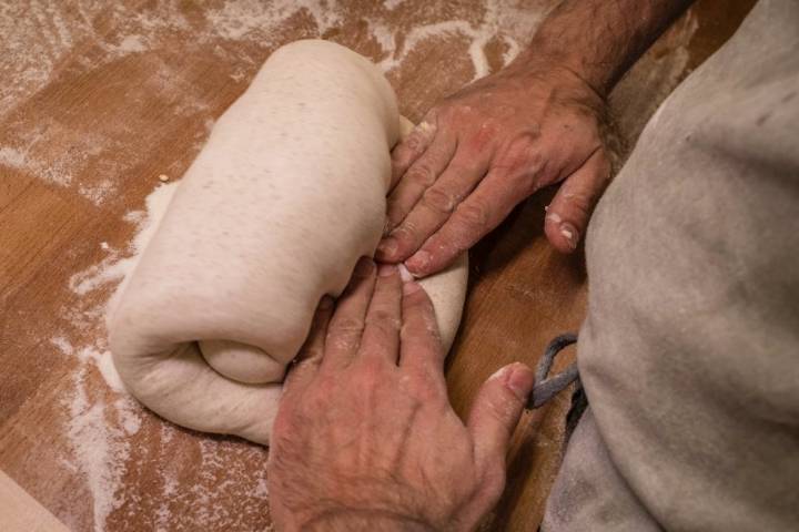 Un panadero hace pliegues a la masa de pan
