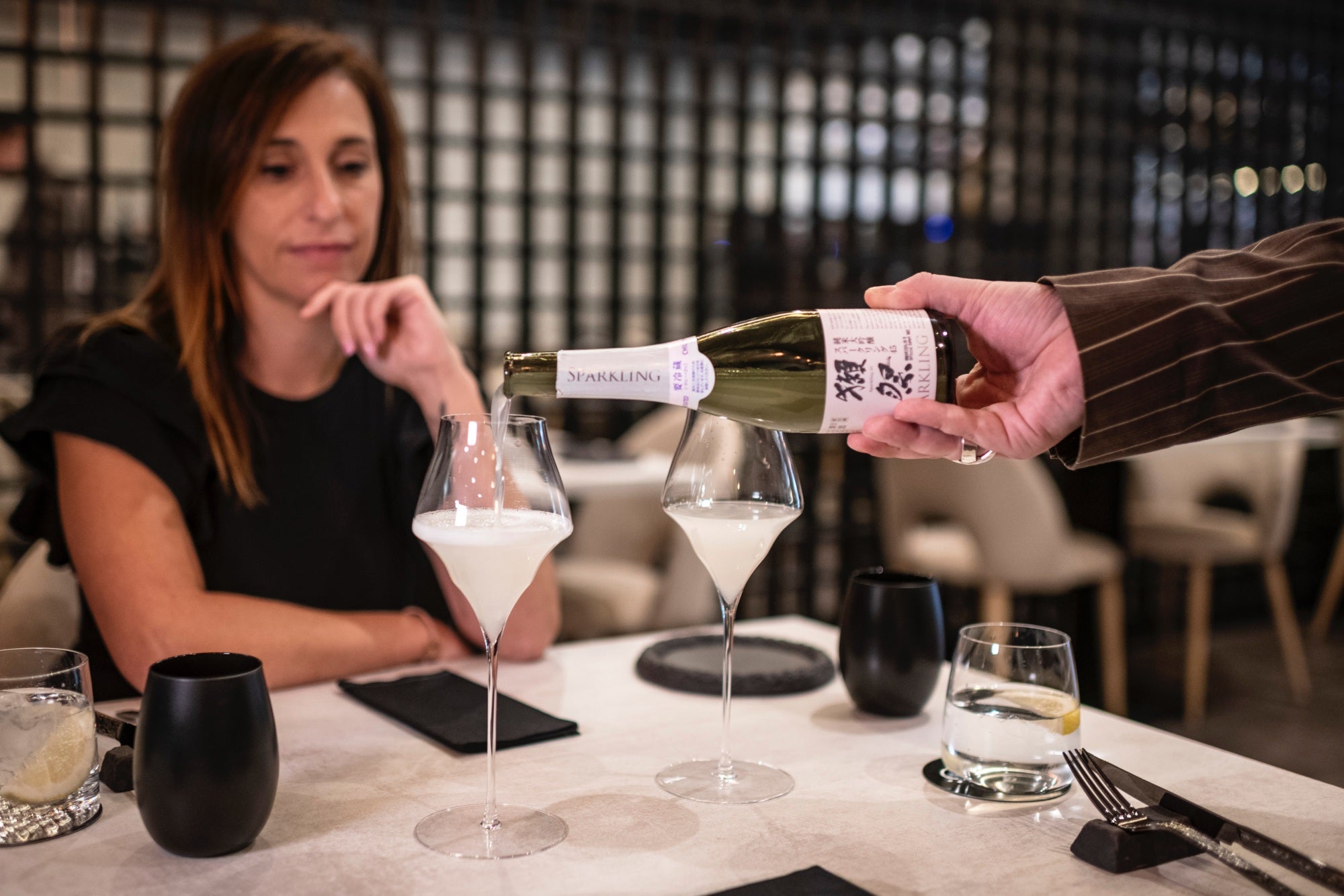 El sumiller sirve dos copas de sake.