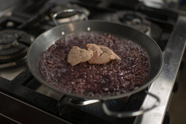 Arroz bomba cocinado a fuego lento con vino tinto y cochino negro confitado.