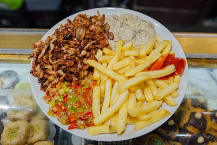 Plato de carne, ensalada de pimientos, baba ganoush (crema de berenjena) y patatas fritas.