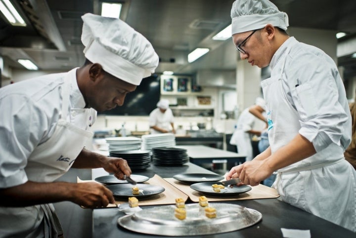 Dos de los cocineros emplatando el milhojas caramelizado de anguila ahumada, foie gras, cebolleta y manzana verde.