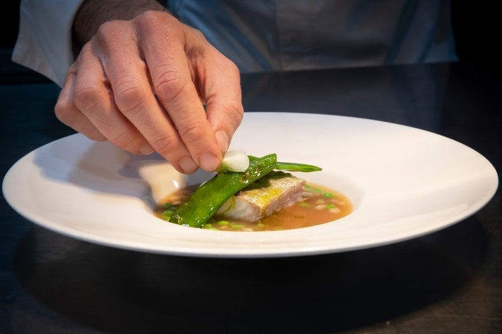 Pureza en el plato: merluza asada a la brasa, jugo de pescado, panceta y guisantes.