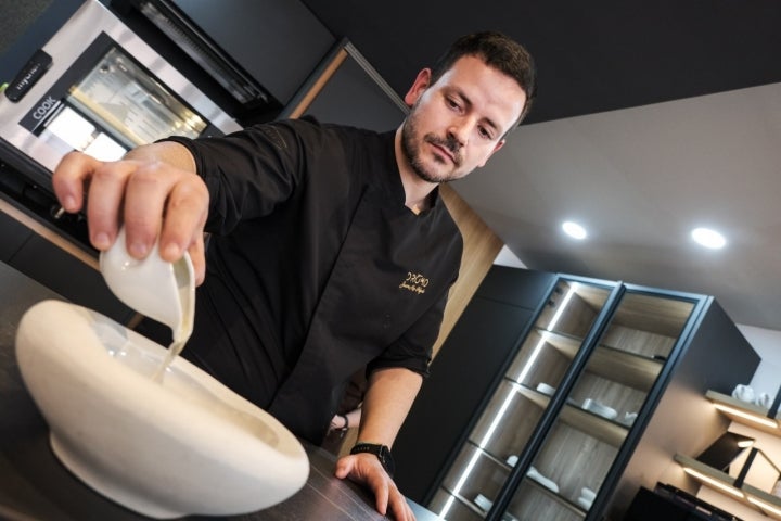 Juanma sirve el consomé de jamón ibérico que acompaña a los fideos.