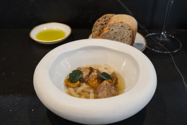 Sopa con yema confitada con daditos de panceta y fideos de piel de cerdo.