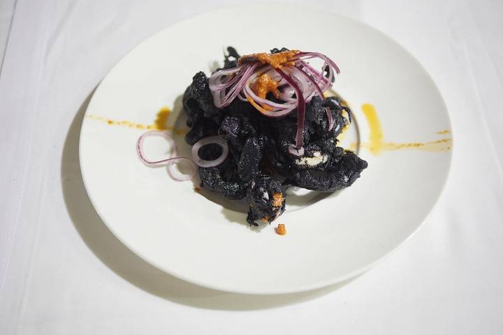 Calamares de "la platjeta" en tempura negra, cebolla laminada y aceite de romesco.