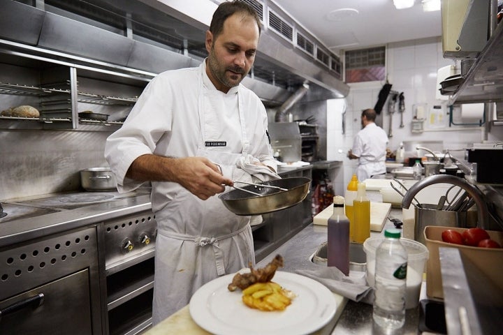 El jefe de cocina acabando un plato de cabrito al horno.