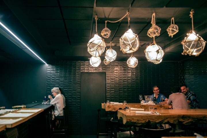 Frente a la cocina vista, las mesas con taburetes altos te permiten ver todo lo que se maquina dentro.