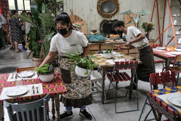 Dos jóvenes preparan las mesas para el servicio de comidas.