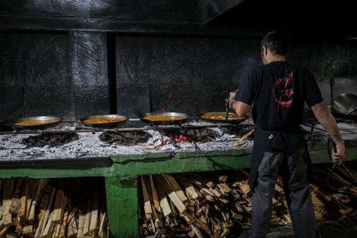 Marcos atento a varias paellas a la vez, cada una en un estadio diferente.