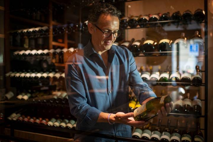 Martinelli eligiendo un vino en la bodega, que combina vinos de autor, de pequeños productores y grandes bodegas.