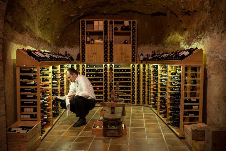 Ramón eligiendo un vino en la bodega, de cientos de años de antiguedad y sobre la que se construyó el restaurante.