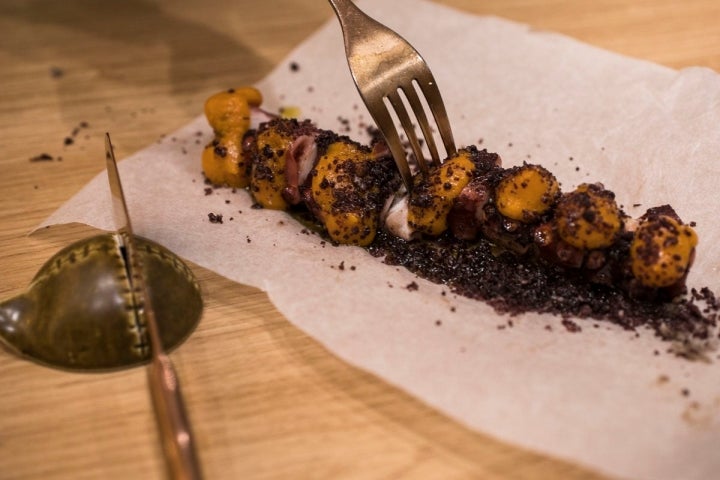 Pulpo a la brasa con emulsión de bonito ahumado y tierra de aceitunas negras.