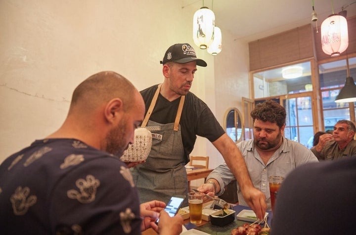 El chef Aitor Olabegoya se acerca a las mesas de los comensales a servir los platos y a charlar con ellos en su restaurante pop up en Poble Sec (Barcelona).