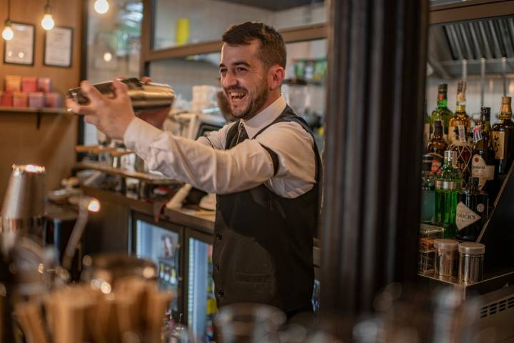El barman, Carlos Novo, se ríe mientras prepara un cóctel.