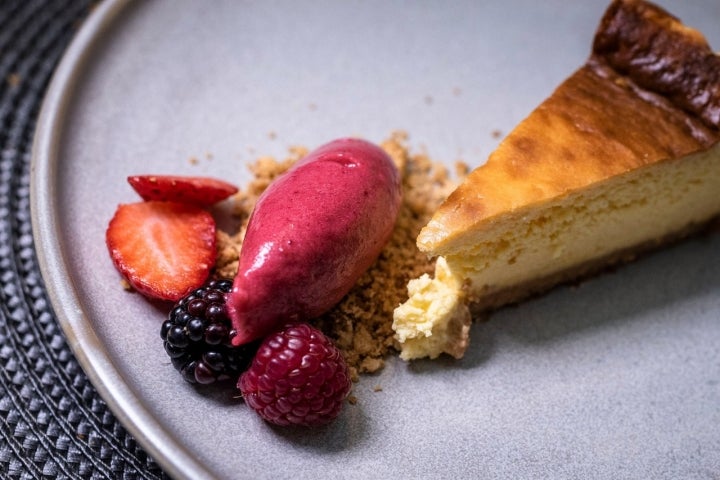 Tarta de queso con crumble de manzana y helado de frutos rojos.