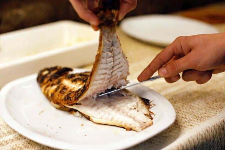 Quitando la raspa a un besugo después de pasarlo por la parrilla, en el 'Bodegón Joxe Mari', en Orio, Guipúzcoa.