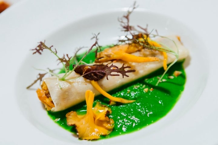 Canelón de bacalao, setas y avellanas sobre una crema de acelgas.