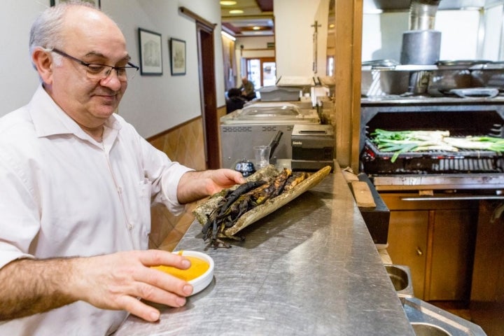 Pedro sirve la tradicional teja con los 'calçots' y la salsa romesco.