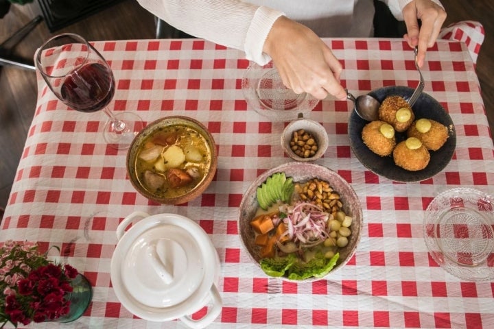 Sobre un mantel de cuadros, varios platos del restaurante peruano El Observatorio, en Valencia.