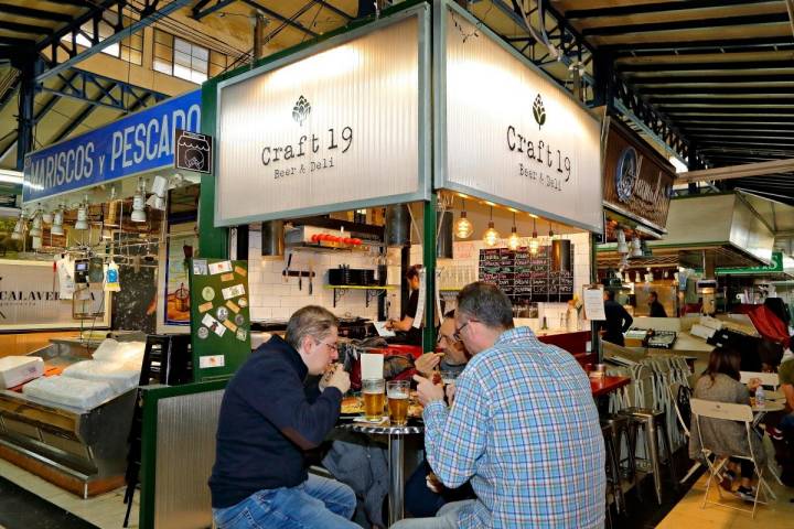 Unos clientes se comen un sándwich en las mesas de 'Craft 19' en el Mercado de Vallehermoso.