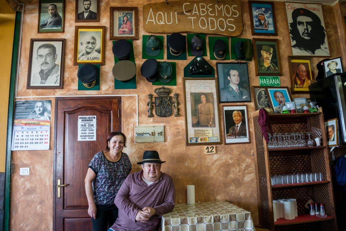 José Eladio y su mujer Nina, junto al mural de 'Bodega Zacatín' cubierta de retratos de dispares dirigintes políticos e idelogógicos.