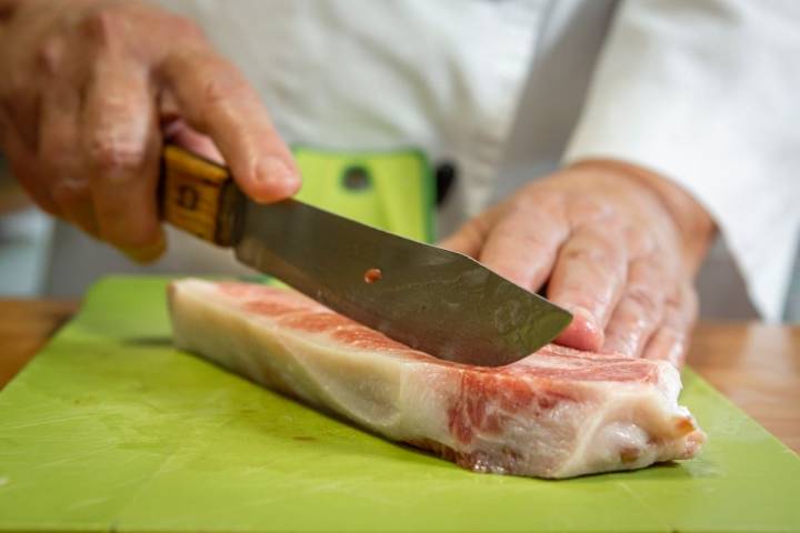 Cortando con un afilado cuchillo un fliete de atún crudo en dados para la receta del poke bowl de atún picante.