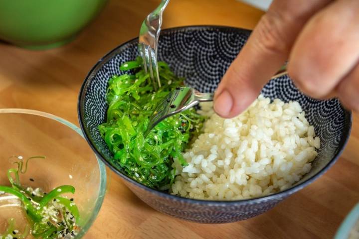 Colocando las algas junto al arroz en el bowl para la receta del poke bowl de atún picante.