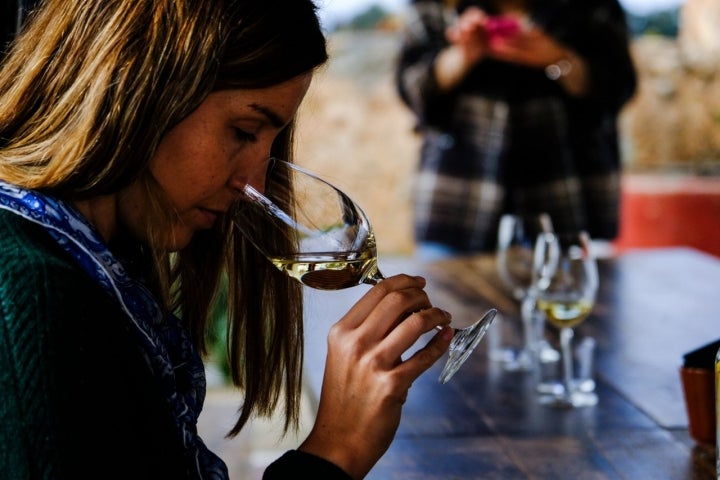 Mujer con copa de vino blanco en la mano.