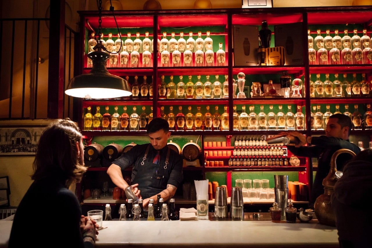 Yeray y Eider preparan bebidas en una barra forrada de botellas con creaciones artesanales.