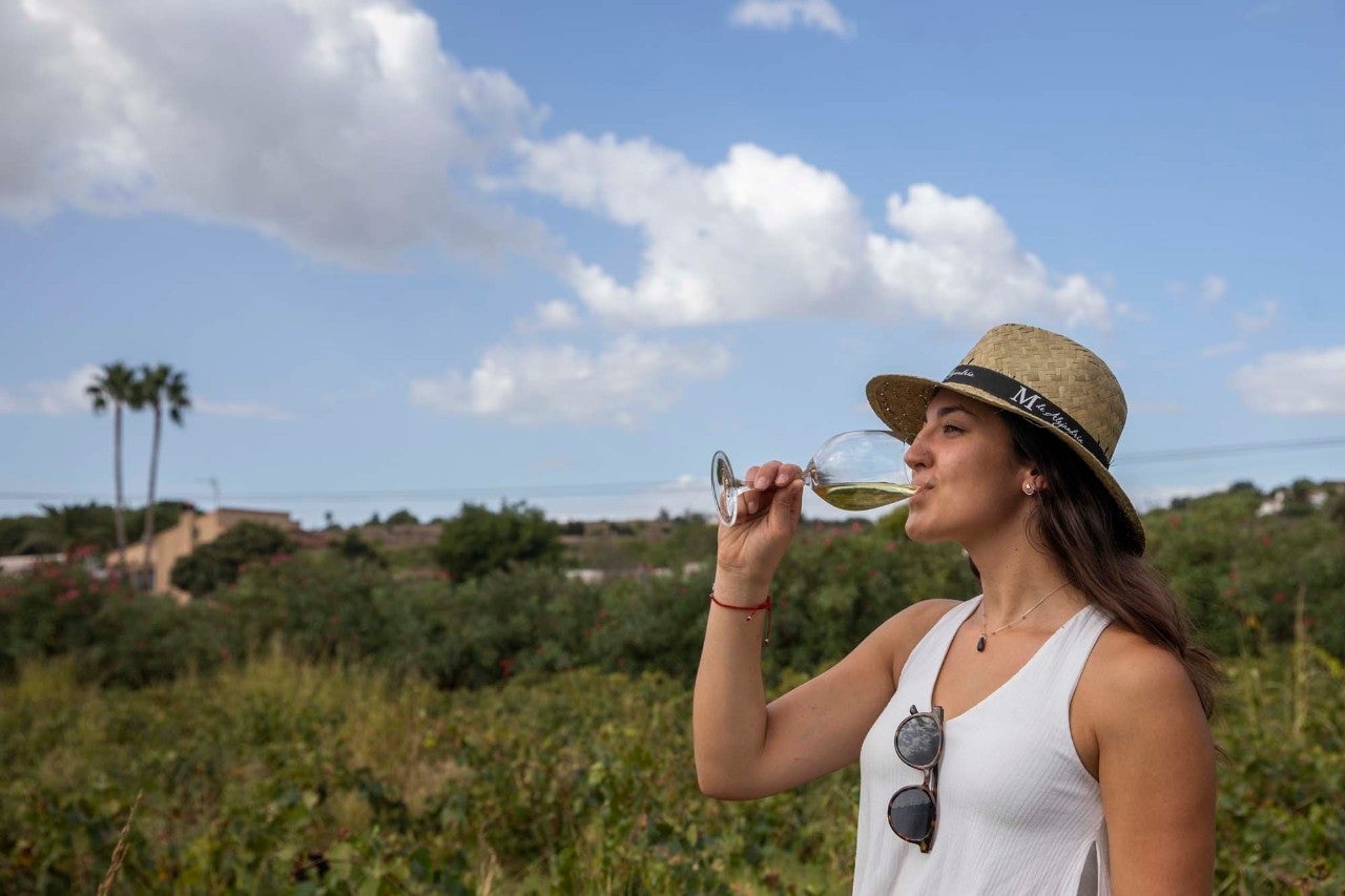 Una chica bebe una copa de vino moscatel en el campo.