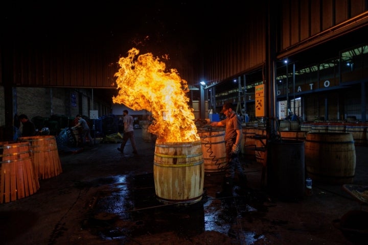 Un operario tuesta el interior de una barrica