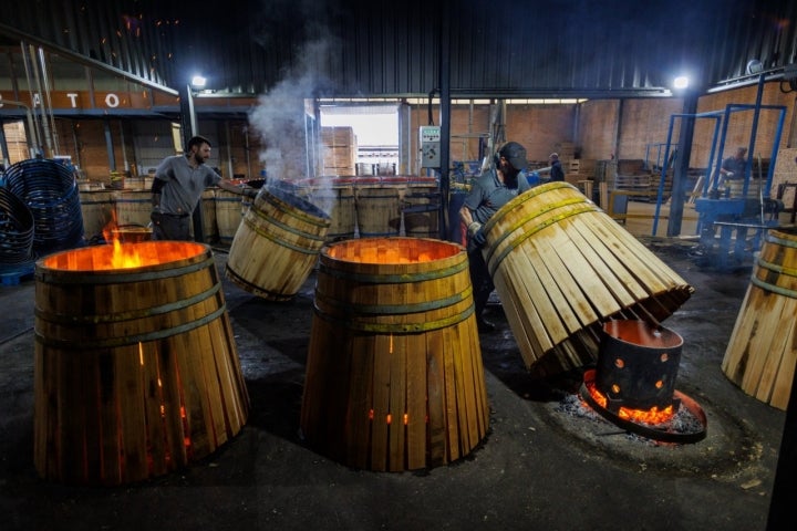 Operarios colocan las barricas, todavía abiertas, al fuego