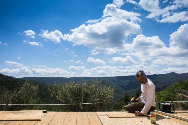 Aberto Ruiz, propietario de la casa rural 'Mar de la Carrasca', en el parque natural de Peñagolosa, Castellón, arregla la tarima para la práctica de yoga con vistas al valle.