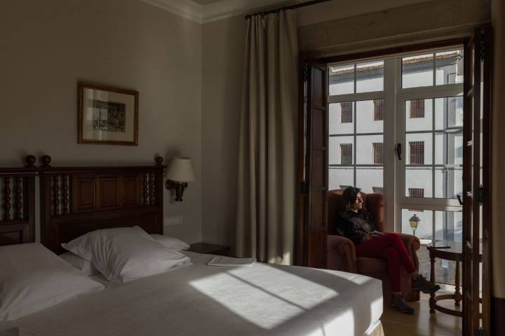 Una mujer lee en la habitación con vistas a la Calle Real, una de las más importantes del barrio de la Magdalena y la ciudad.