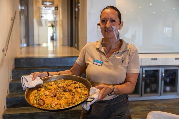 Una mujer muestra una paella valenciana.