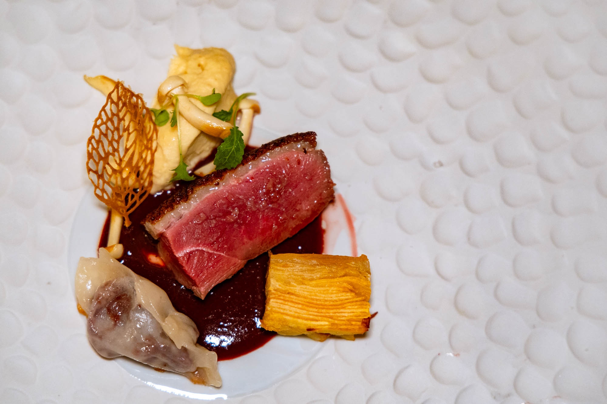Magret de pato con salsa de vino tinto, milhojas de manzana, ‘dumpling’ de morcilla, puré de apionabo y setas.