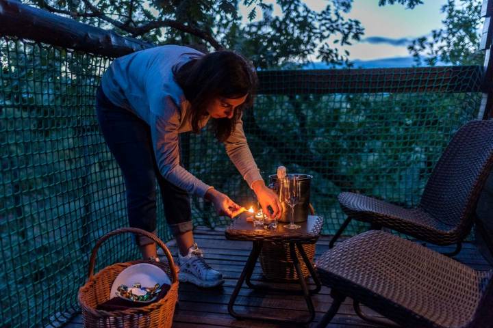 Una chica enciende unas velas en la terraza de la cabaña.