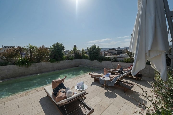 Varias personas toman el sol en la piscina en el rooftop