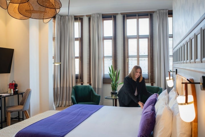Una mujer coloca un cojín en la cama de la habitación.