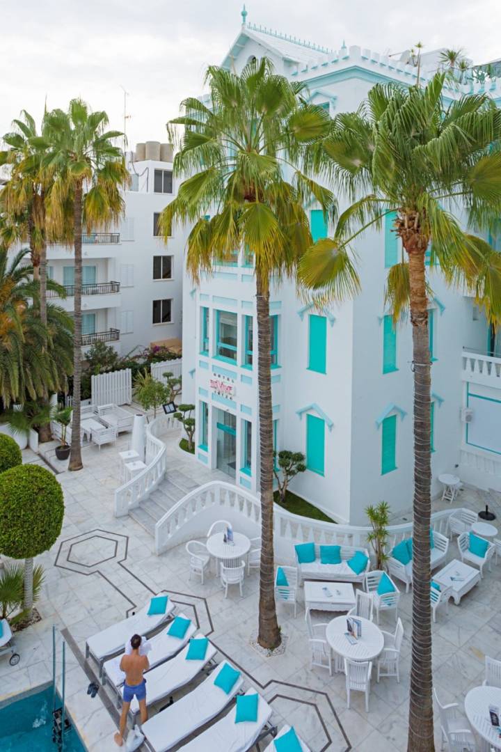 Vista de la fachada blanca y las palmeras del hotel Es Viver (Ibiza).