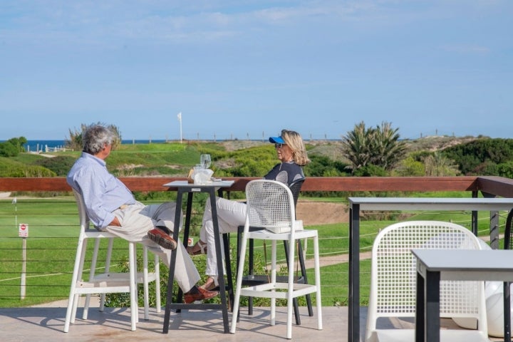 Una pareja disfruta de una de las terrazas con vistas al campo de golf y al mar.