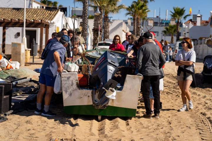 Varias personas rodean una barca de pescadores en el Barrio de los Pescadores de Islantilla (Huelva)