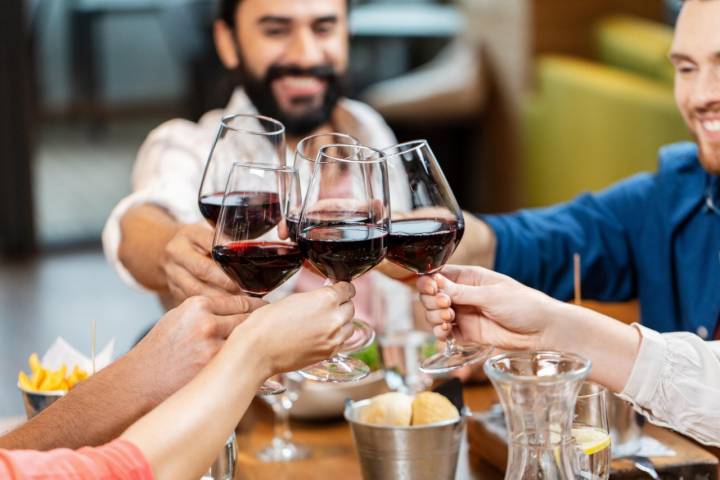 happy friends drinking red wine at restaurant