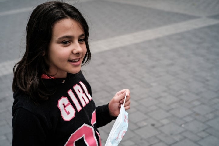 Una niña se quita la mascarilla jugando.