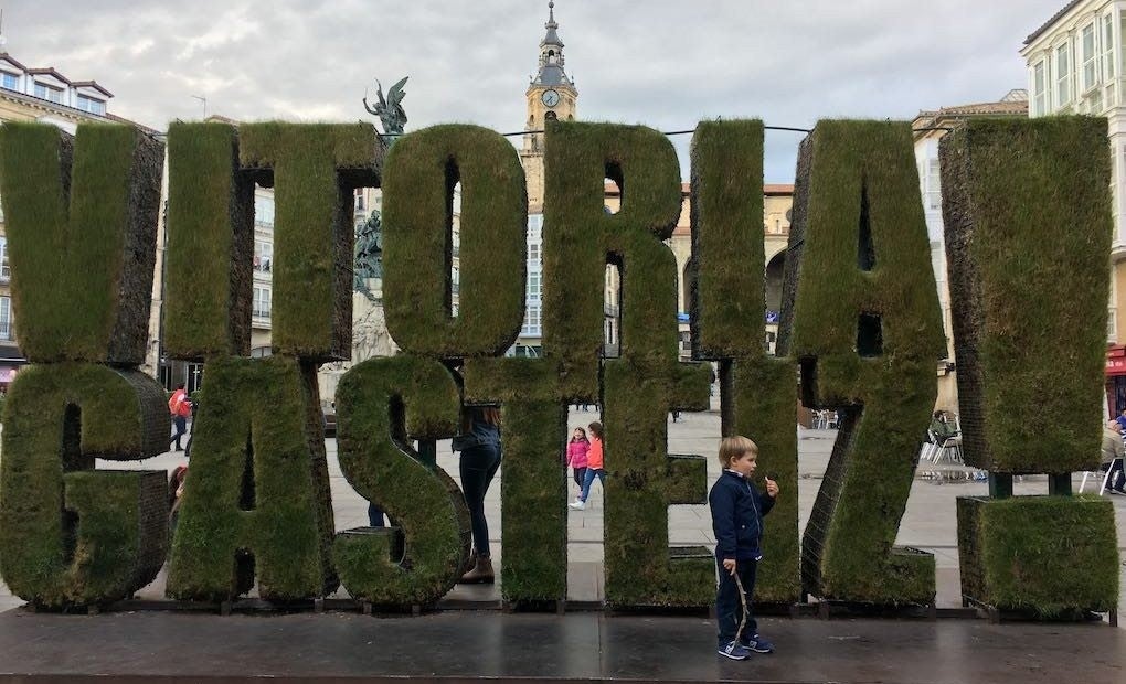 Frente a la escultura vegetal de la plaza de la Virgen Blanca.