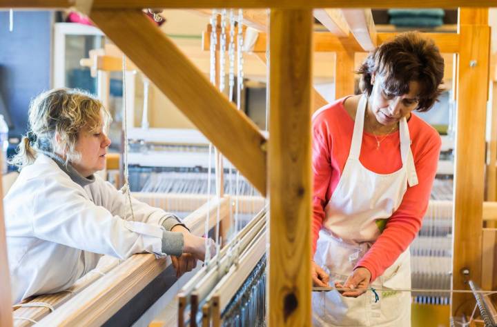 Dos tejedoras trabajan en el taller integrado en el Monasterio