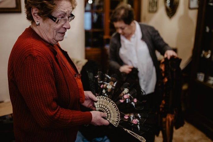 Gloria enseña un abanico de viuda mientras María busca entre los trajes de época que tienen.