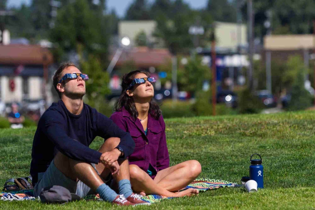Pareja mirando al sol con gafas especiales para eclipses.