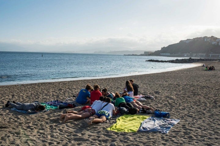 Grupo de jóvenes tumbados en la Playa de la Ribera.